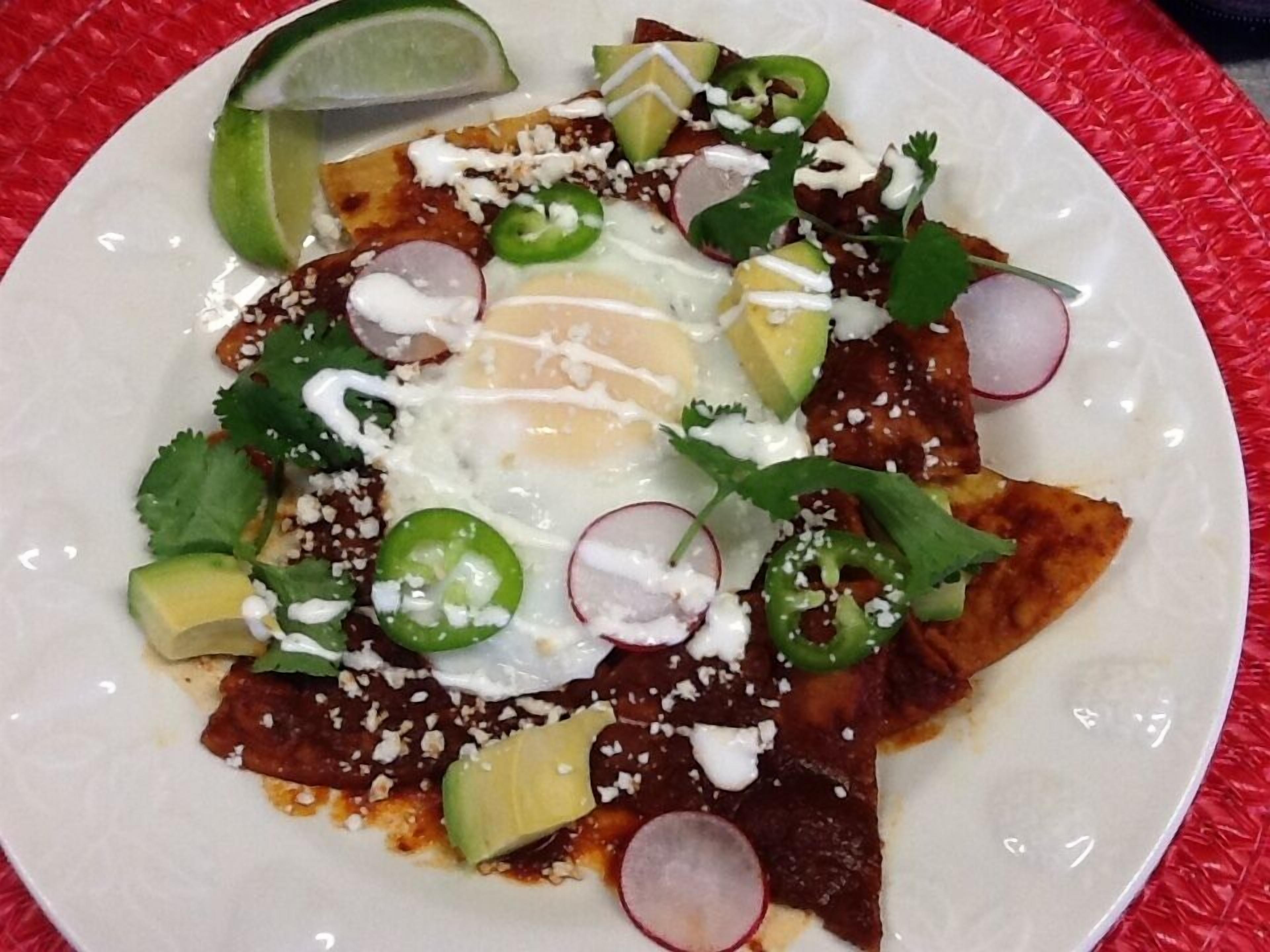 Un plato de nachos cubiertos de queso, jalapeños, rábanos y un huevo frito.