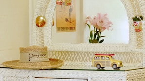 A white wicker vanity with a mirror, a hat, a toy car, and a pair of sandals. - Featherbed Railroad B&B Resort (Nice)