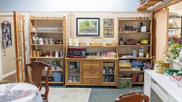 A cozy room with a dining table, chairs, a wooden cabinet with various items, and a bookshelf filled with books and decorative objects.