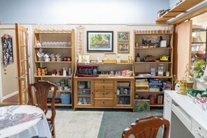 Una habitación acogedora con una mesa de comedor, sillas, un aparador de madera con objetos varios y una estantería llena de libros y adornos.