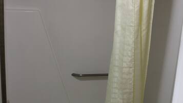 A bathroom with a bathtub, toilet, and shower curtain.