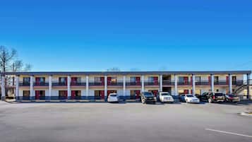A motel with a two-story structure, multiple balconies, and a parking lot with several cars.