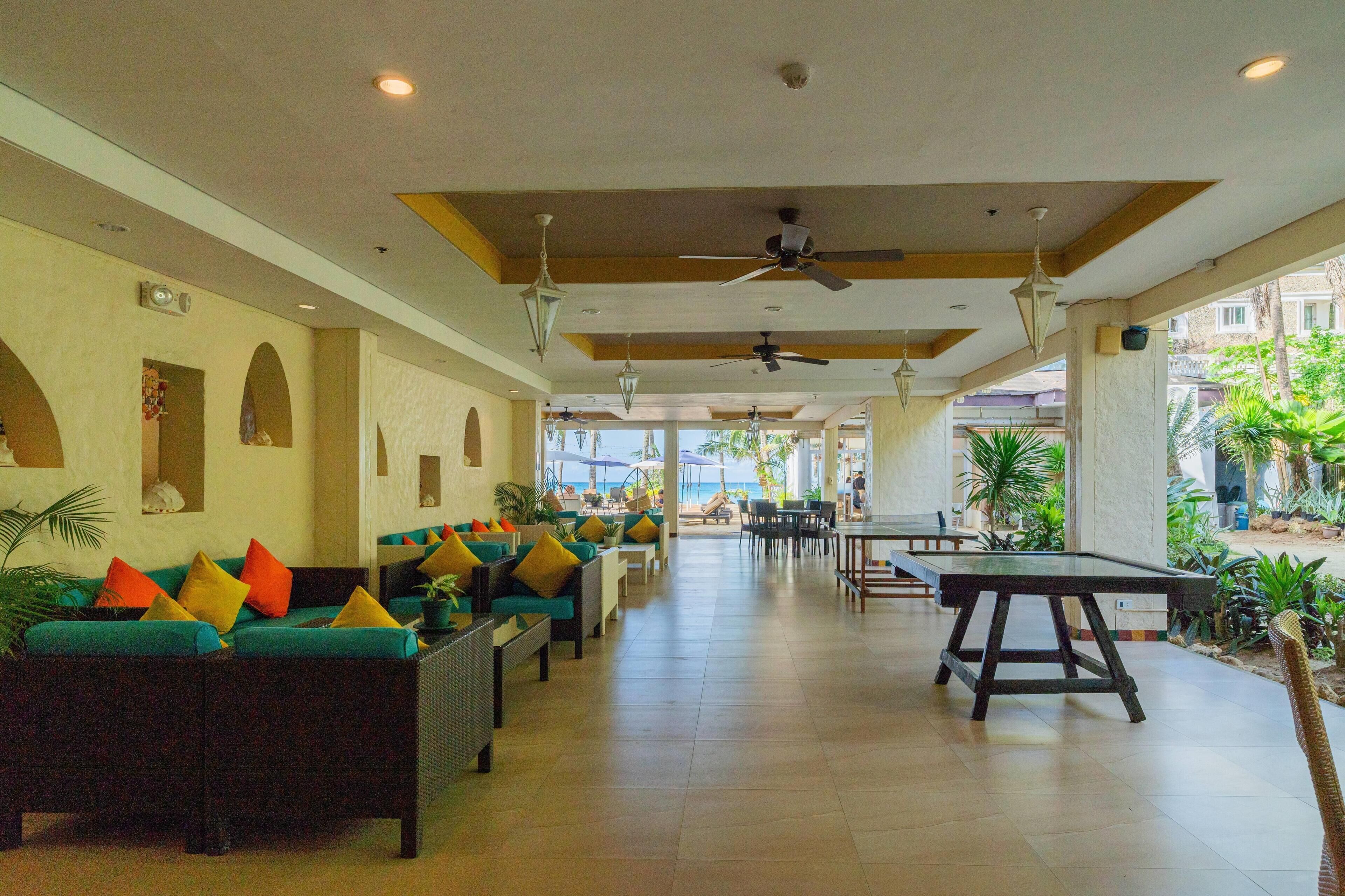 A spacious indoor area with seating arrangements and a ping pong table, featuring a view of the outdoors.
