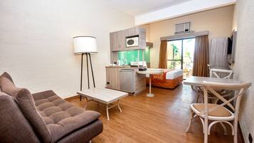 A compact living space with a sofa, a small table, a dining area, and a kitchenette.