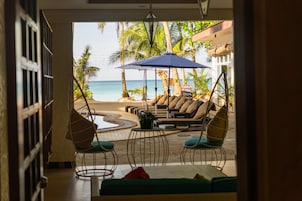 Un espacio de descanso frente a la playa con vistas al océano, asientos al aire libre y un letrero que anuncia una especialidad filipina.