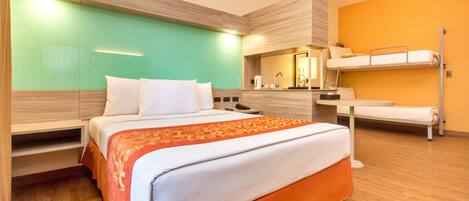 A hotel room with a bed, a bunk bed, a ceiling fan, and a bathroom with a mirror and sink.