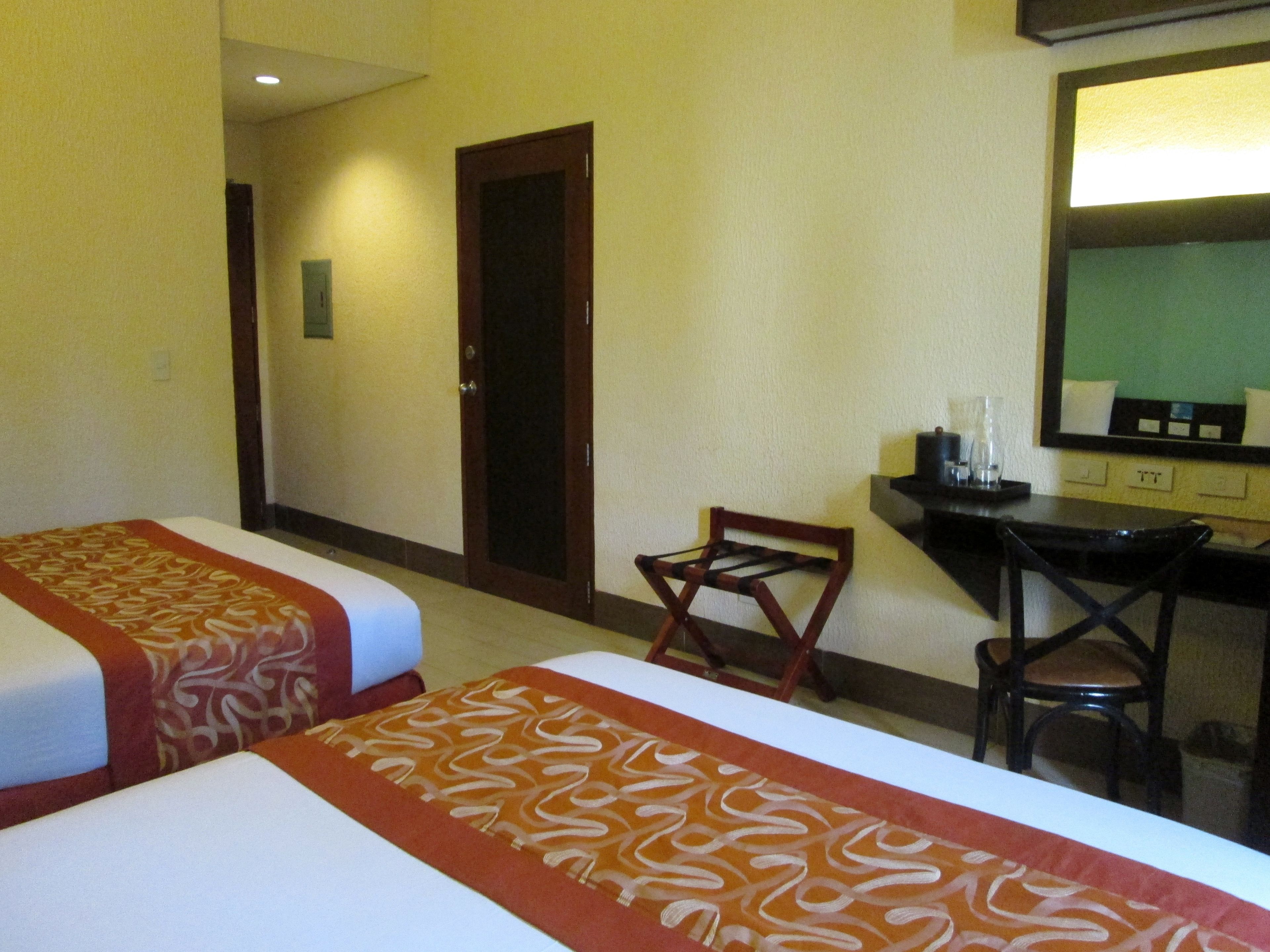 A hotel room with two beds, a desk, and a chair.