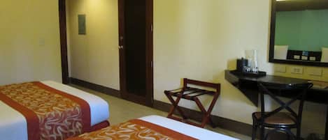 A hotel room with two beds, a desk, and a chair.