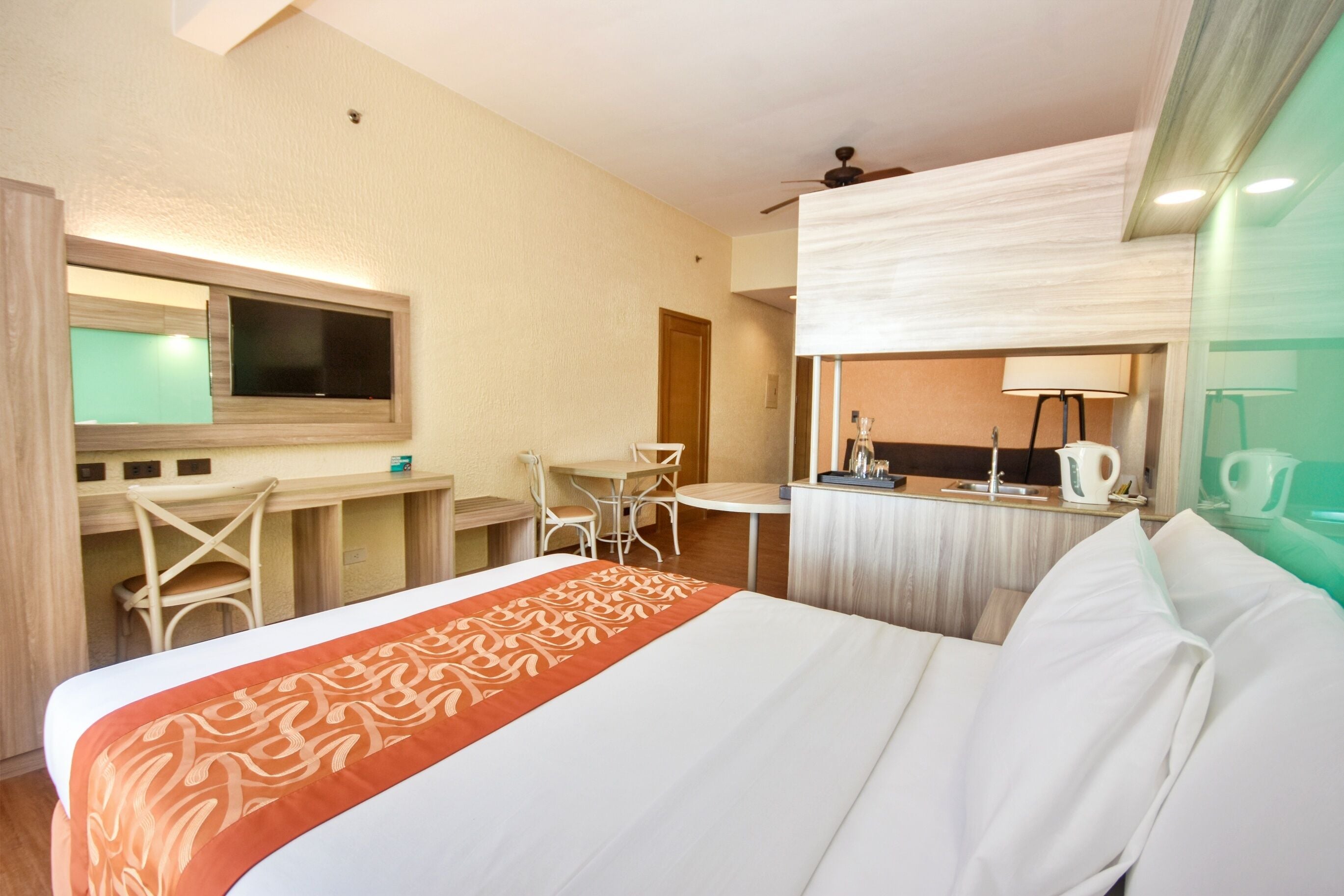 Hotelkamer met een bed, een bureau, een stoel, een kleine tafel, een spiegel en een raam.