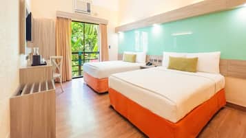 A hotel room with two beds, a desk, a chair, and a view of greenery outside.