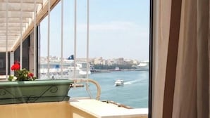 Una habitación con vista al mar y al paisaje urbano.