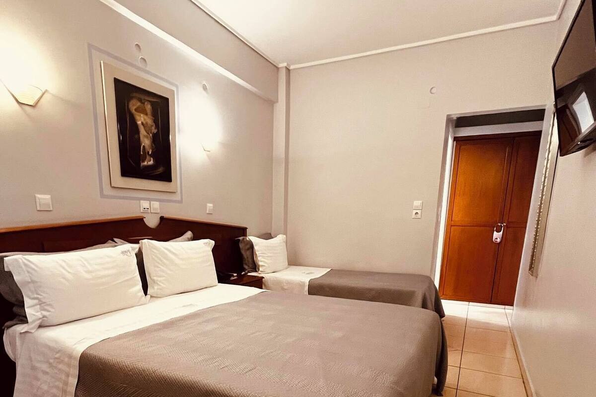 Una habitación de hotel con una cama grande, una cama más pequeña, un cuadro en la pared y una puerta con la llave en la cerradura.