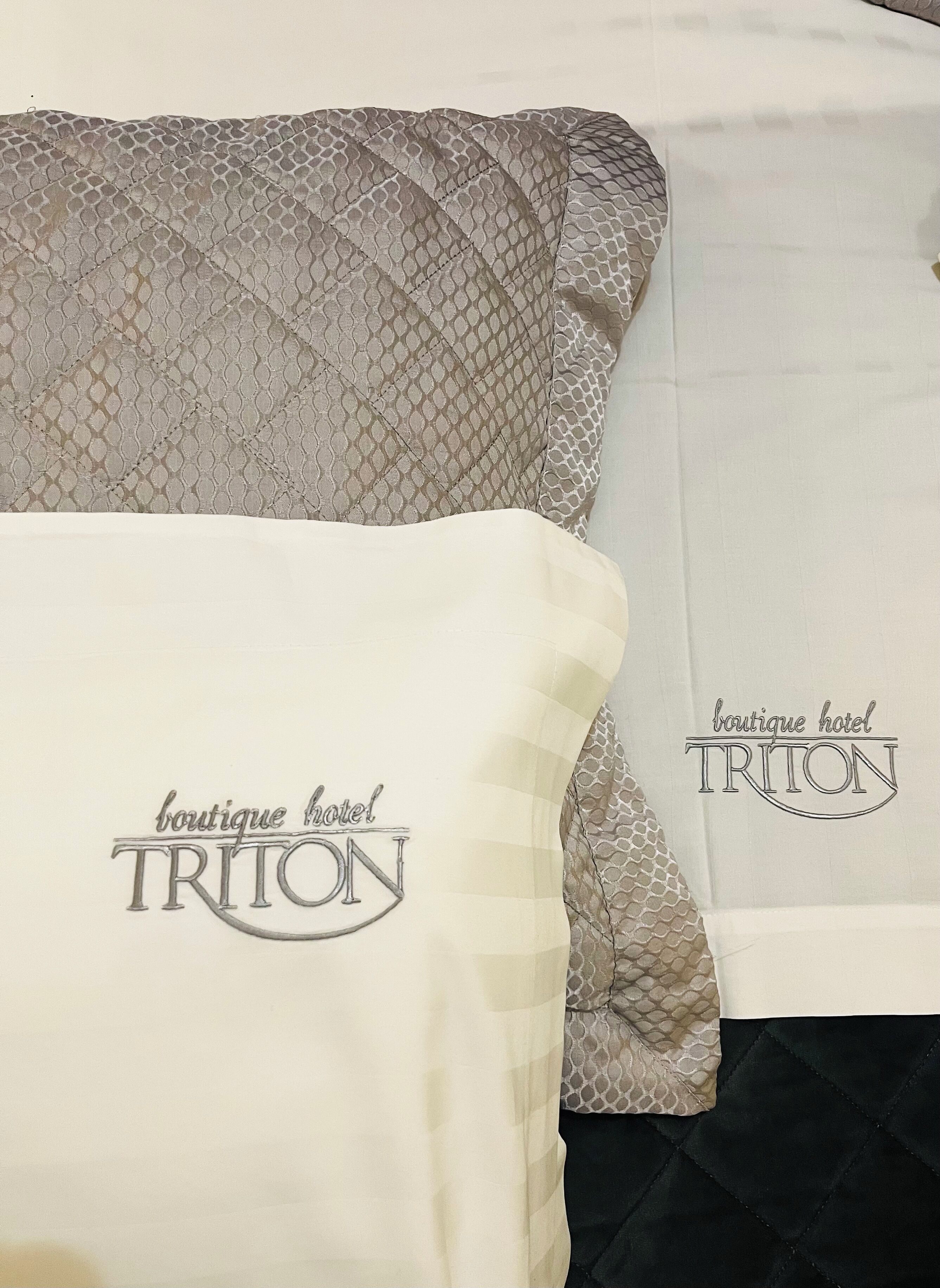 Ein Bettwäsche-Set mit dem Aufdruck 'boutique hotel TRITON'.