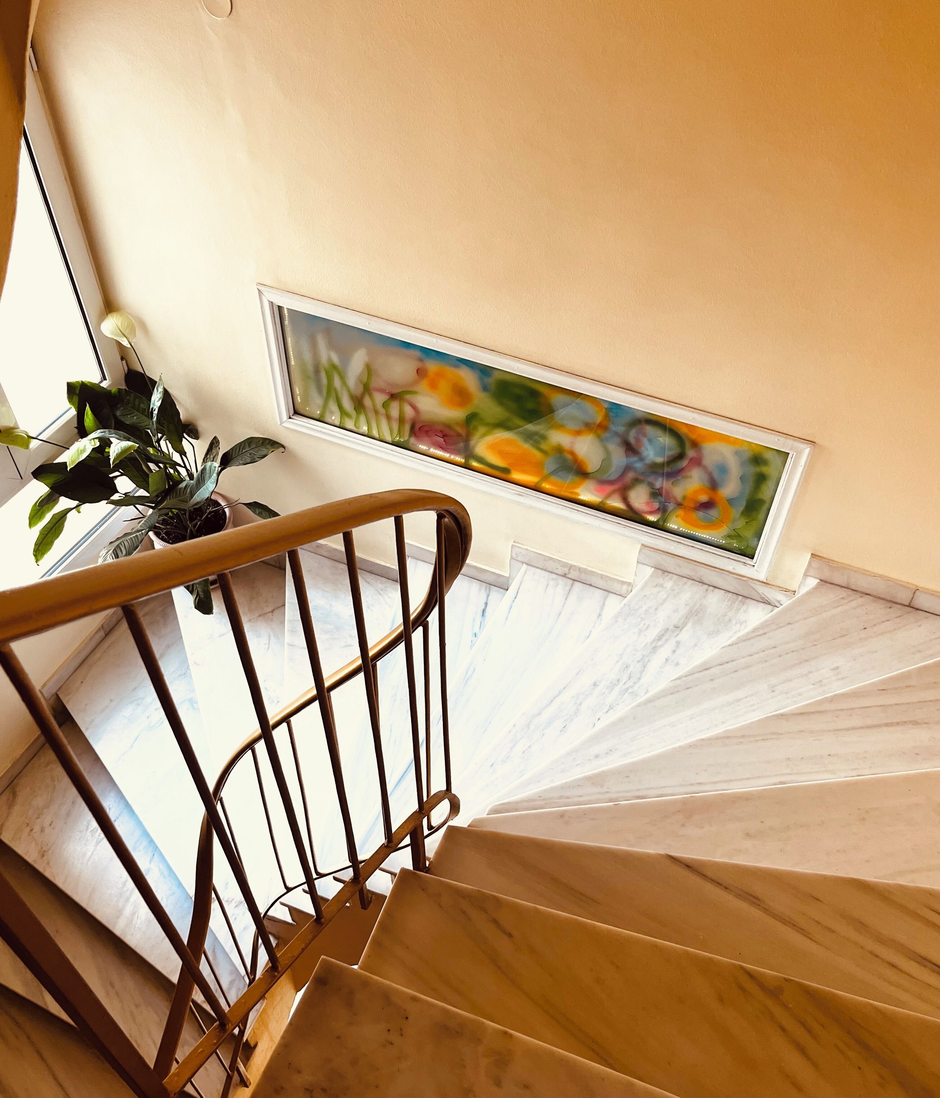 Uma escada com corrimão de madeira e vista para um quadro na parede.