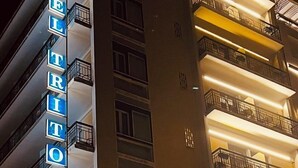 Un hotel de varios pisos con señalización iluminada que dice "HOTEL TRITON".