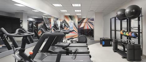 A gym with treadmills, stationary bikes, and exercise balls.