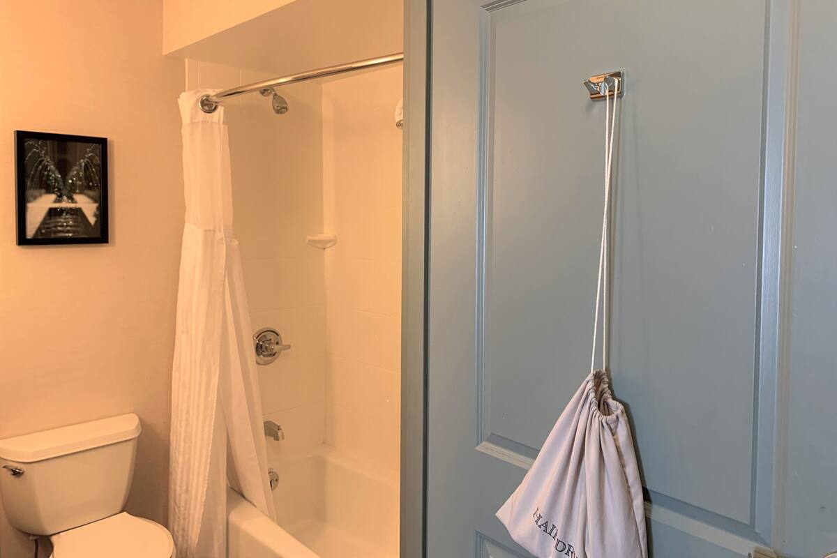 A bathroom with a white toilet, a shower with a glass door, and a towel hanging on a hook.