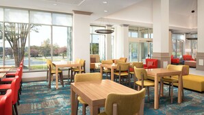 A spacious hotel lobby with multiple seating areas, large windows offering views of the outdoors, and a modern interior design.