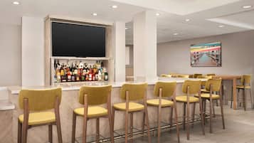 A bar area with multiple stools and a shelf of bottles.