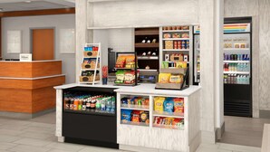 A hotel reception area with a self-service beverage station, snack vending machines, and a minibar.