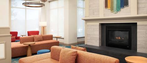 A modern living room with a fireplace, sofas, and a large window.