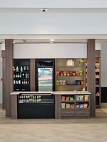 A self-service beverage kiosk with refrigerated and non-refrigerated drink options, snack shelves, and a clean, modern design.