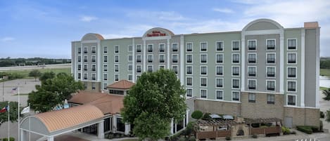 A large hotel with a central courtyard, multiple floors, and a covered entrance.