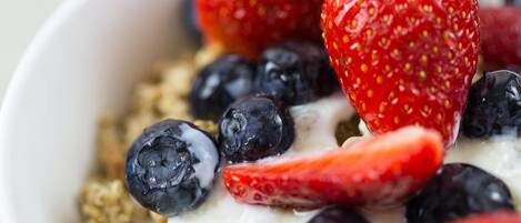 A bowl of yogurt with strawberries and blueberries.