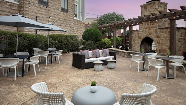 An outdoor patio area with seating arrangements, tables, and string lights. - Hilton Garden Inn Dallas Lewisville (Lewisville)