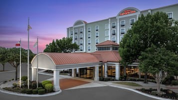 Un hotel con entrada cubierta, varios pisos y un letrero que indica que es un Hilton Garden Inn.