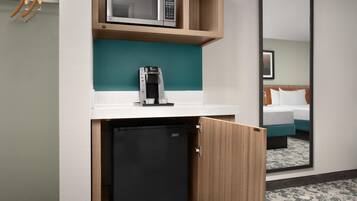 Una kitchenette compacta equipada con microondas, cafetera y un refrigerador pequeño.