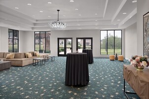 A spacious room with a large sofa, a round table, and a chandelier.