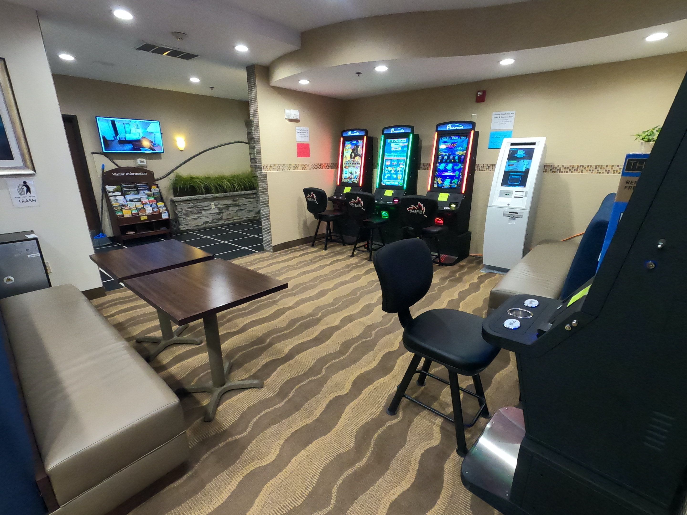 Un espace de jeux équipé de plusieurs bornes d’arcade, d’un téléviseur et de différents types de sièges.