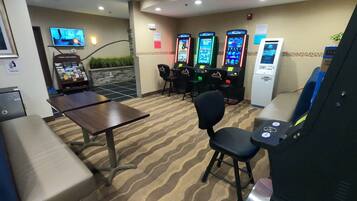 Un espace de jeux équipé de plusieurs bornes d’arcade, d’un téléviseur et de différents types de sièges.