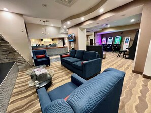 A hotel lobby with a reception desk, seating area, and gaming machines. - HomeTowne Studios & Suites By Red Roof Washington (Washington)