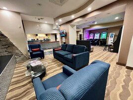 Vestíbulo de hotel con recepción, zona de estar y máquinas recreativas.