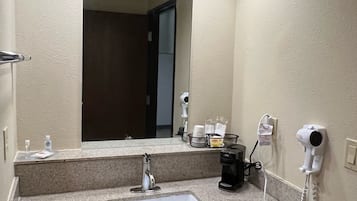 Ein Badezimmer mit Waschbecken, Spiegel und einem an der Wand befestigten Fön.