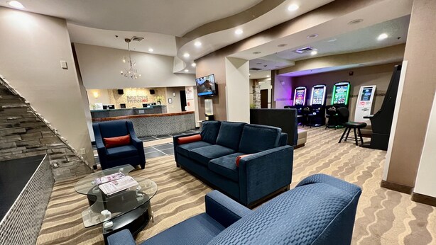 A lobby with sofas, a reception desk, and gaming machines.