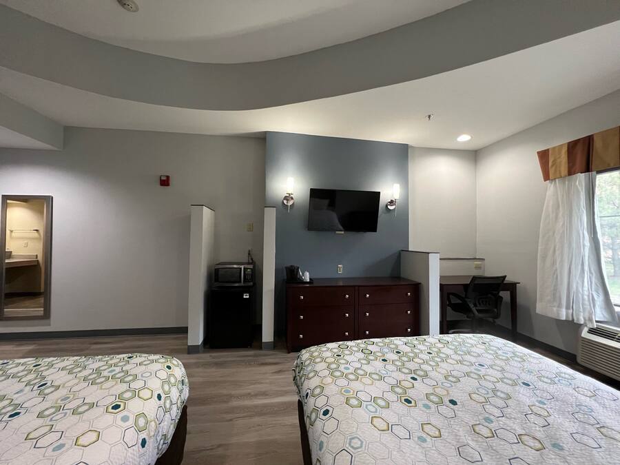 Een hotelkamer met twee bedden, een televisie, een bureau en een kledingkast.