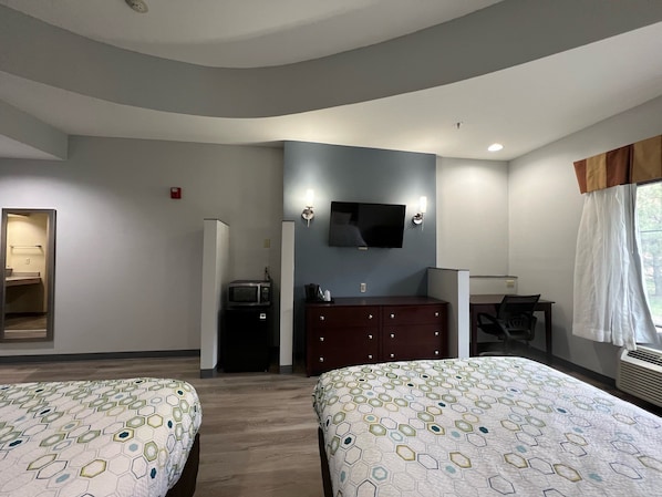A hotel room with two beds, a TV, a desk, and a wardrobe. - HomeTowne Studios & Suites By Red Roof Washington (Washington)