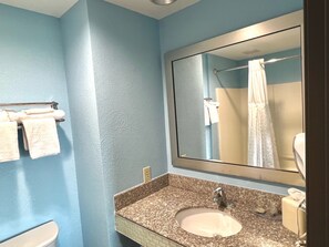 A bathroom with a sink, mirror, and towel rack. - HomeTowne Studios & Suites By Red Roof Washington (Washington)