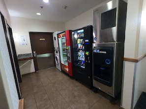 A hallway with a vending machine, a washing machine, and an ice dispenser. - HomeTowne Studios & Suites By Red Roof Washington (Washington)