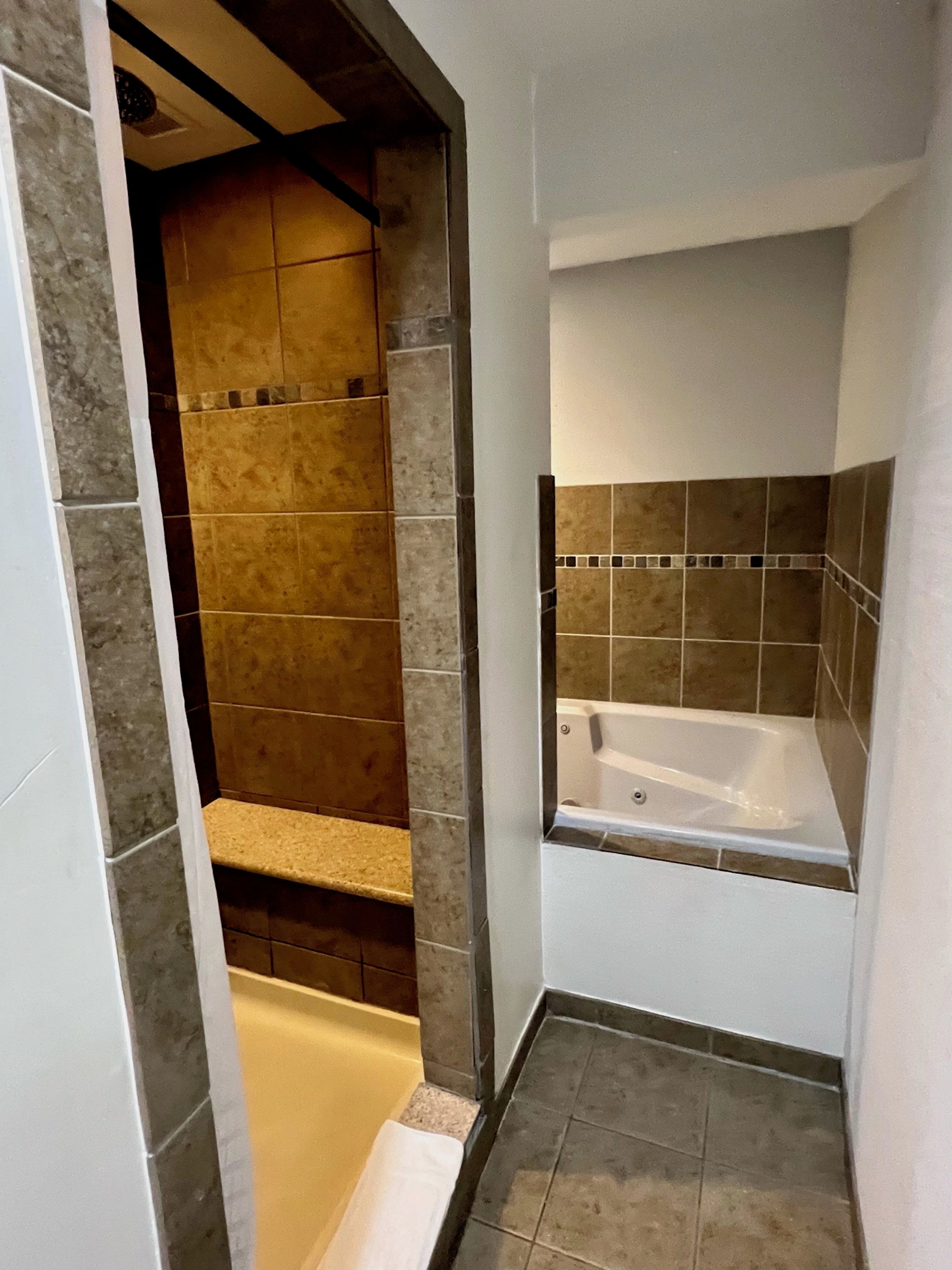 A bathroom with a bathtub, a shower area, and a tiled floor.