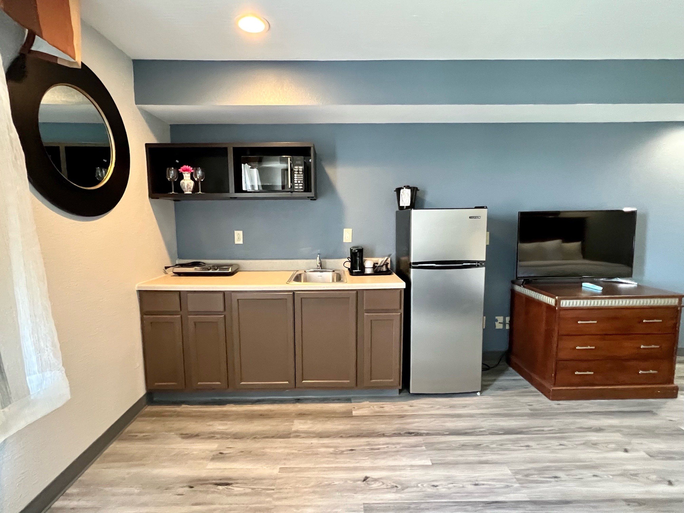A compact kitchen with a refrigerator, microwave, and wooden cabinets.