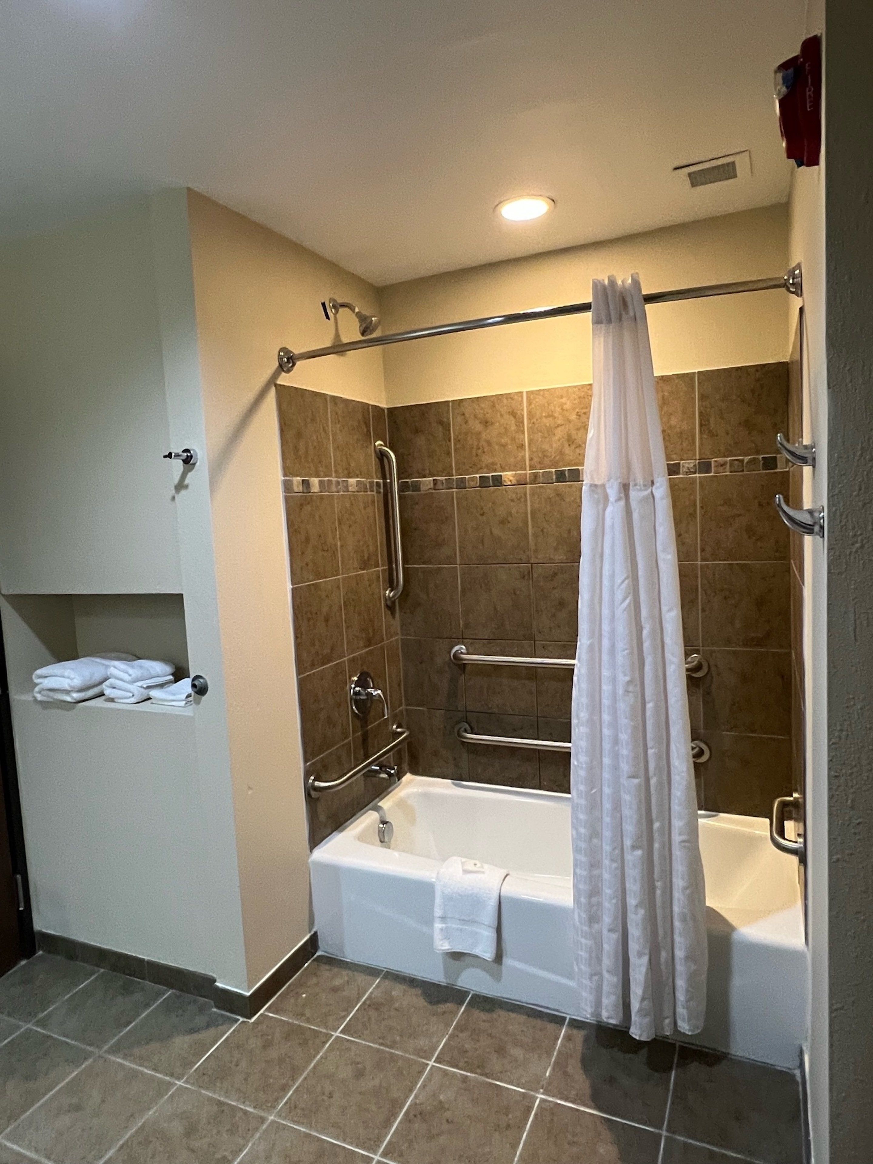 A bathroom with a bathtub, a shower with a glass door, and a towel rack.