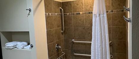 Un baño con bañera, ducha con puerta de vidrio y un perchero para toallas.