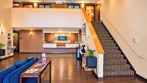 A hotel lobby with a reception desk, a staircase, seating area, and a water dispenser. - Manitou Pikes Peak Hotel (Manitou Springs)