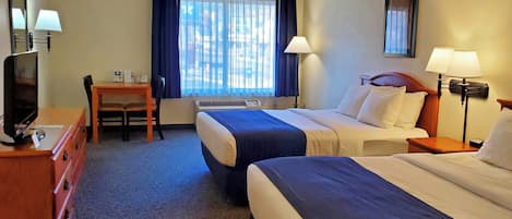 A hotel room with two beds, a desk, a chair, a television, and a window with curtains.