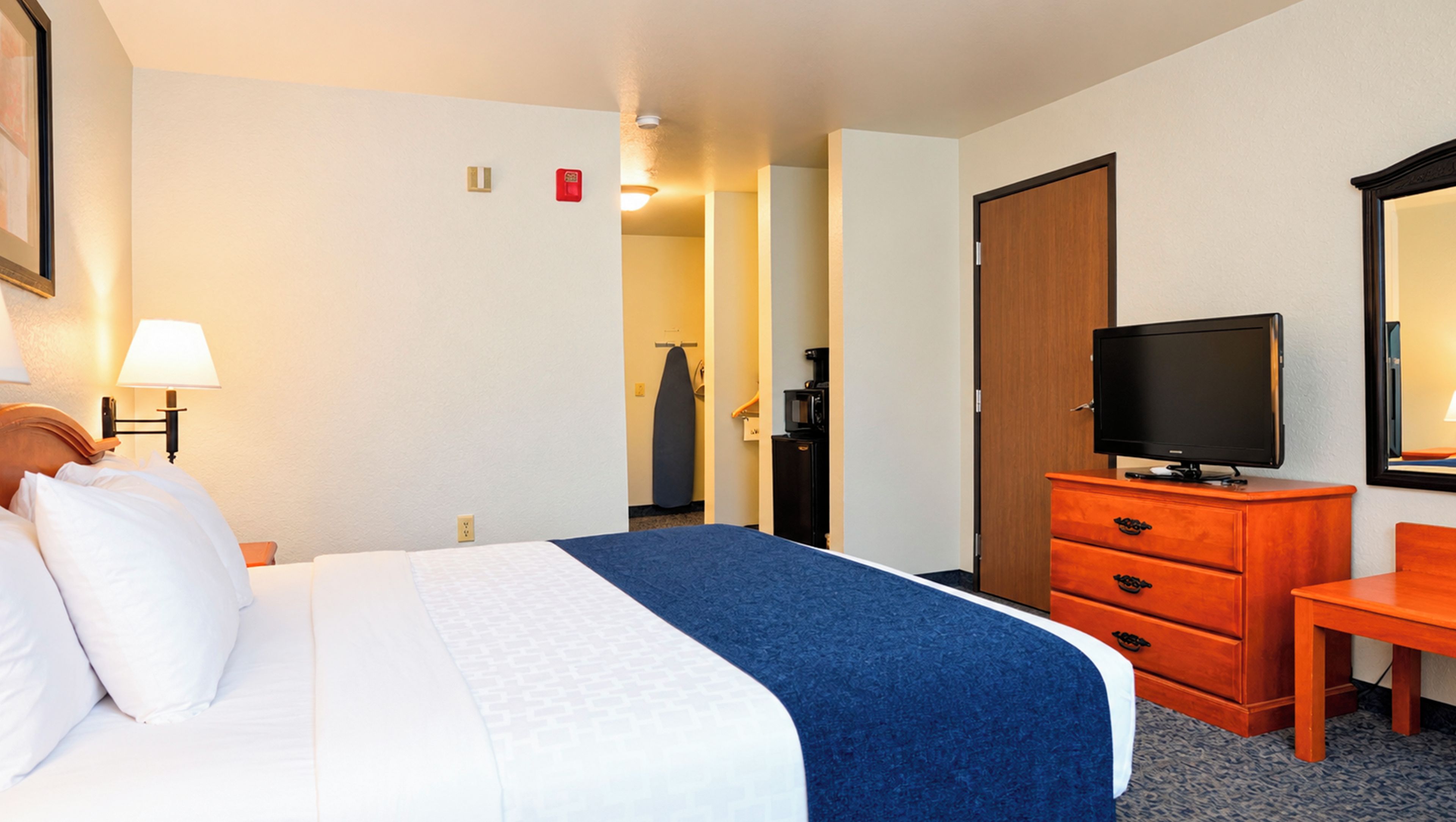 Una habitación de hotel con una cama, un televisor, un tocador y un espejo.