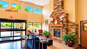 A lobby with a stone fireplace, seating area, and an exit sign.